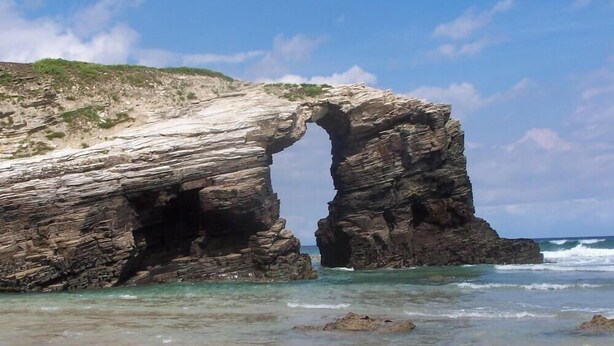 Una formación rocosa natural con un gran arco sobre el océano.