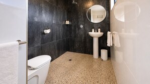 Un baño moderno con inodoro, lavamanos y ducha.