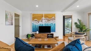 A living room with a flat-screen TV, a coffee table, a sofa, and a large painting on the wall. - Copa Panorama Apartment (Copacabana)