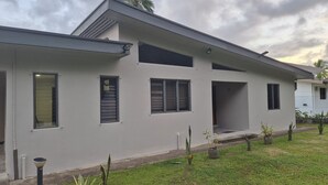 A modern two-story house with a flat roof, large windows, and a small front porch.