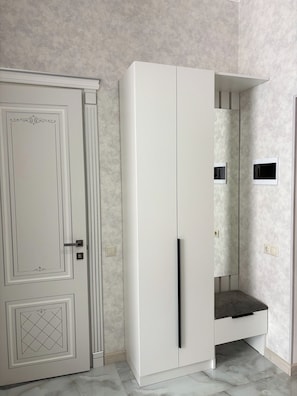 Una habitación con un armario blanco, una puerta con un panel decorativo y un interruptor de luz en la pared.