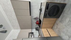 Eine kleine Küche mit Waschmaschine, Spüle und Arbeitsplatte.