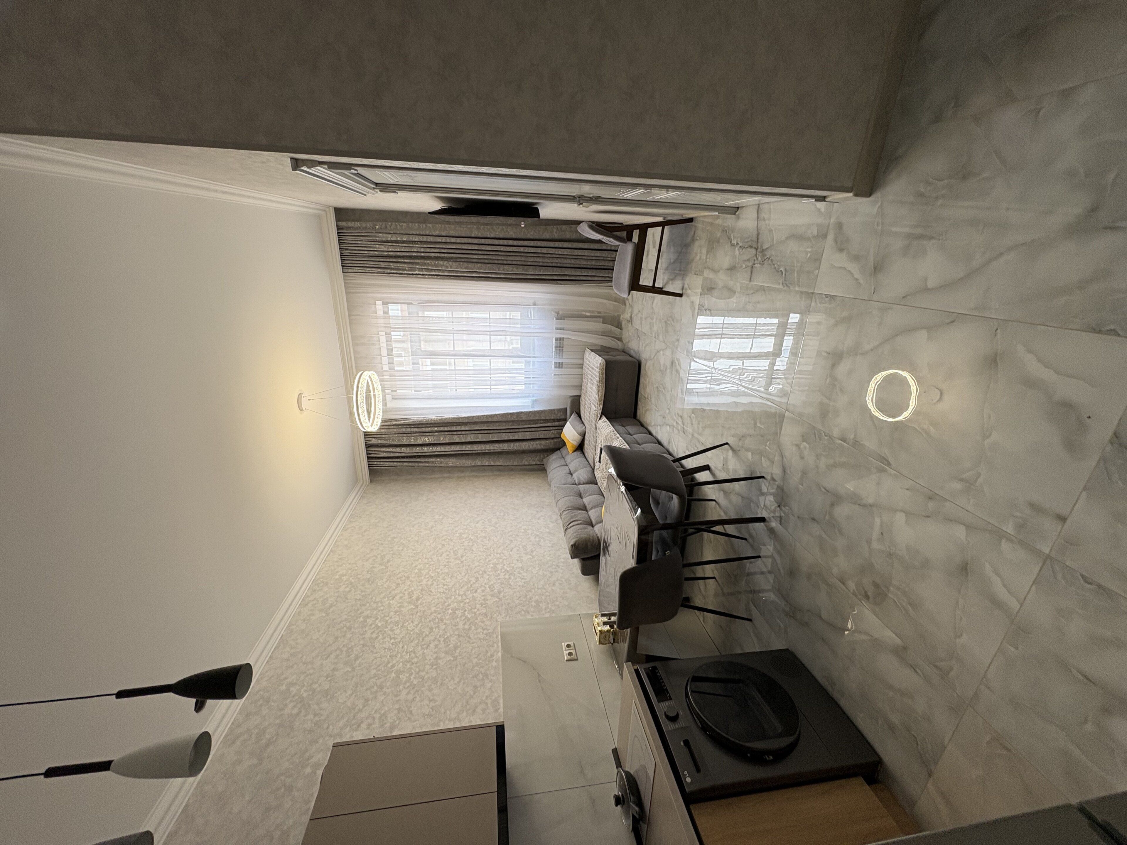 A compact living space with a sofa, a dining table, and a small kitchen area.