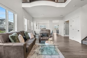 A spacious living room with a leather sofa, a glass coffee table, and a view of the outside.