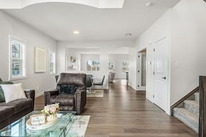 A spacious living room with a leather sofa, a glass coffee table, and a dining area in the background.