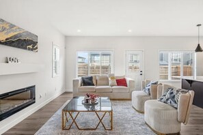 A modern living room with a sofa, armchairs, a coffee table, and a fireplace.
