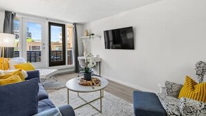 A modern living room with a sofa, armchair, coffee table, and a TV mounted on the wall. - Bright Beltline Suite, Sleeps 4, Free Parking (Calgary)