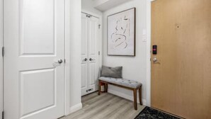 A hallway with white doors, a bench, a framed abstract artwork, and a wooden door. - Bright Beltline Suite, Sleeps 4, Free Parking (Calgary)