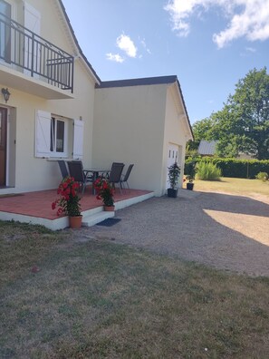 A two-story building with a balcony, a gravel driveway, and potted plants. - Gite La thébaïde (Thoury)