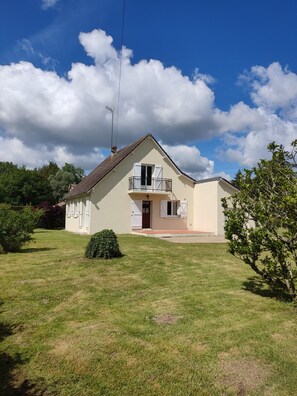 A single-story house with a balcony, a small front yard, and a clear sky. - Gite La thébaïde (Thoury)