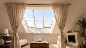 Una camera da letto con un velux, un camino e un mobile cassettiera in legno.