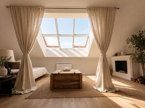 A bedroom with a skylight, a fireplace, and a wooden chest of drawers. - Designer Sky View Loft (Prague)