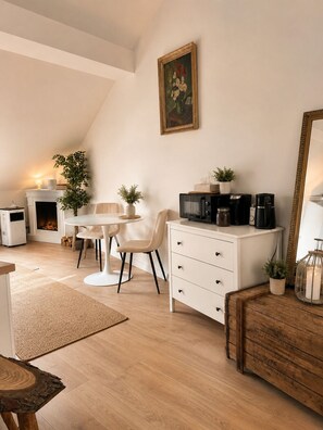 A cozy living room with a fireplace, a dining table, a white sofa, a coffee machine, and a mirror. - Designer Sky View Loft (Prague)