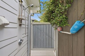 A residential outdoor area with a metal gate, a hose, and a blue water container. - Bluefish House • Six-Seater Golf Cart • Walk to Beach • Private Hot Tub (Santa Rosa Beach)