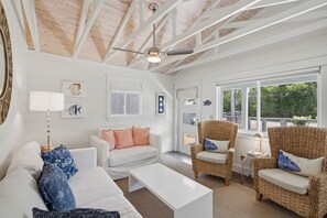 A spacious living room with a high ceiling, white walls, and a large window offering a view of the outdoors. - Bluefish House • Six-Seater Golf Cart • Walk to Beach • Private Hot Tub (Santa Rosa Beach)
