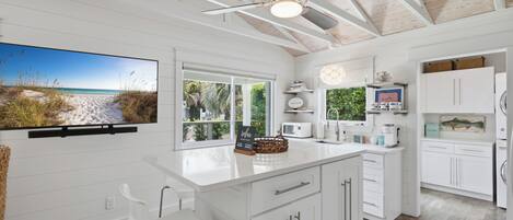 A modern kitchen with white cabinetry, a large island, and a ceiling fan.