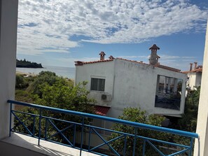 Un edificio costero con techo de tejas rojas, una pequeña torre y un balcón con barandillas azules.