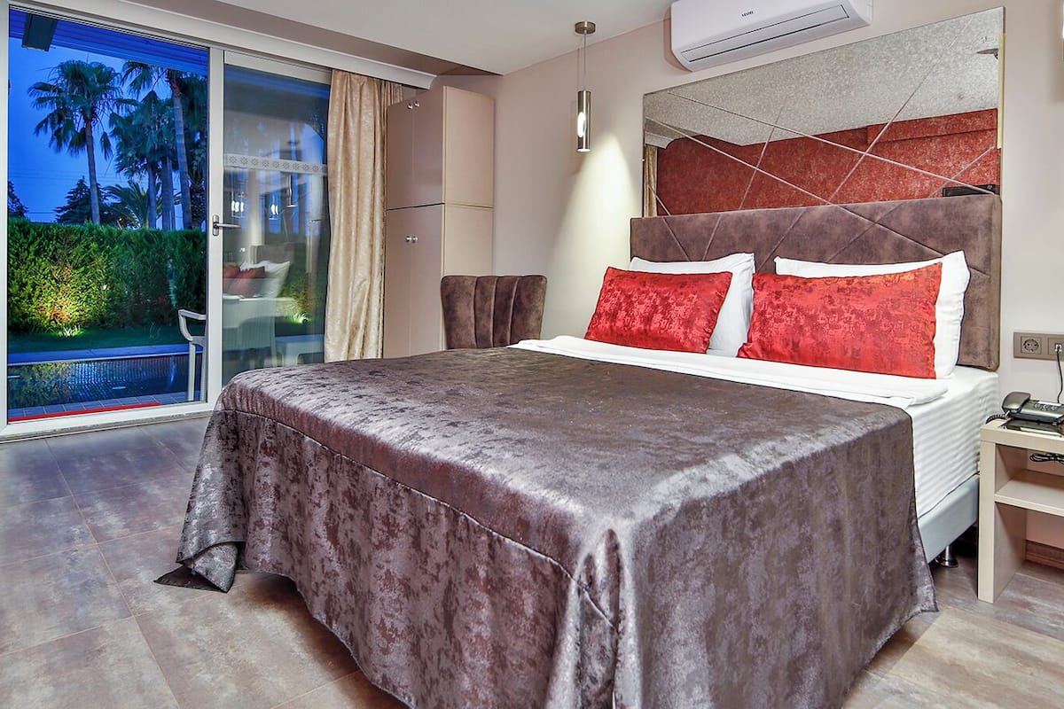 Une chambre d’hôtel moderne avec un grand lit, une vue sur la piscine et un balcon.