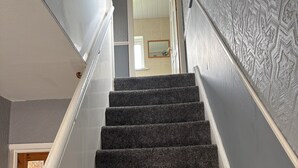 A staircase with carpeted steps leading to a room with a mirror and a door. - Blyth City Delight Free Parking (Blyth)
