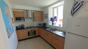 Een keuken met houten kastjes, een fornuis, een magnetron, een spoelbak en een koelkast.