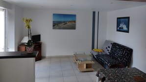 Een woonkamer met een bank, een salontafel, een televisie en een plant.
