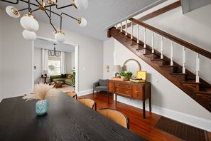 Uma sala de jantar com uma mesa de madeira escura, um vaso e uma escada com corrimãos de madeira.