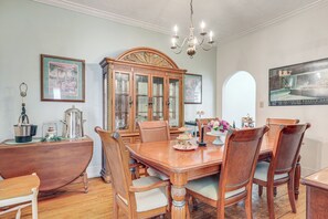 A dining room with a wooden table, chairs, a chandelier, and a large wooden cabinet.