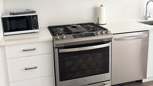 Une cuisine moderne équipée d’un four à micro-ondes encastré, d’une cuisinière à gaz, d’un four et d’un lave-vaisselle.