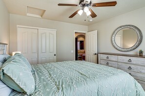 Ein Schlafzimmer mit Bett, Kommode, Deckenventilator und Spiegel.