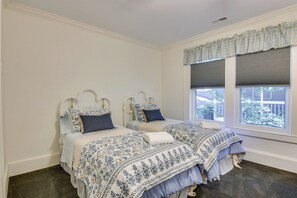 Ein Schlafzimmer mit zwei Betten, einem Fenster mit Jalousien und Blick ins Freie.