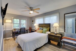 A bedroom with a bed, bedside tables, a desk, a chair, a ceiling fan, and a window with blinds. - Home w/ Fenced Yard, 13 Mi to Kansas City Stadium! (Kansas City)