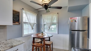 A kitchen with a round wooden table, two bar stools, a stainless steel refrigerator, and a ceiling fan. - KC Stadium Gateway: Home w/ Private Yard (Kansas City)