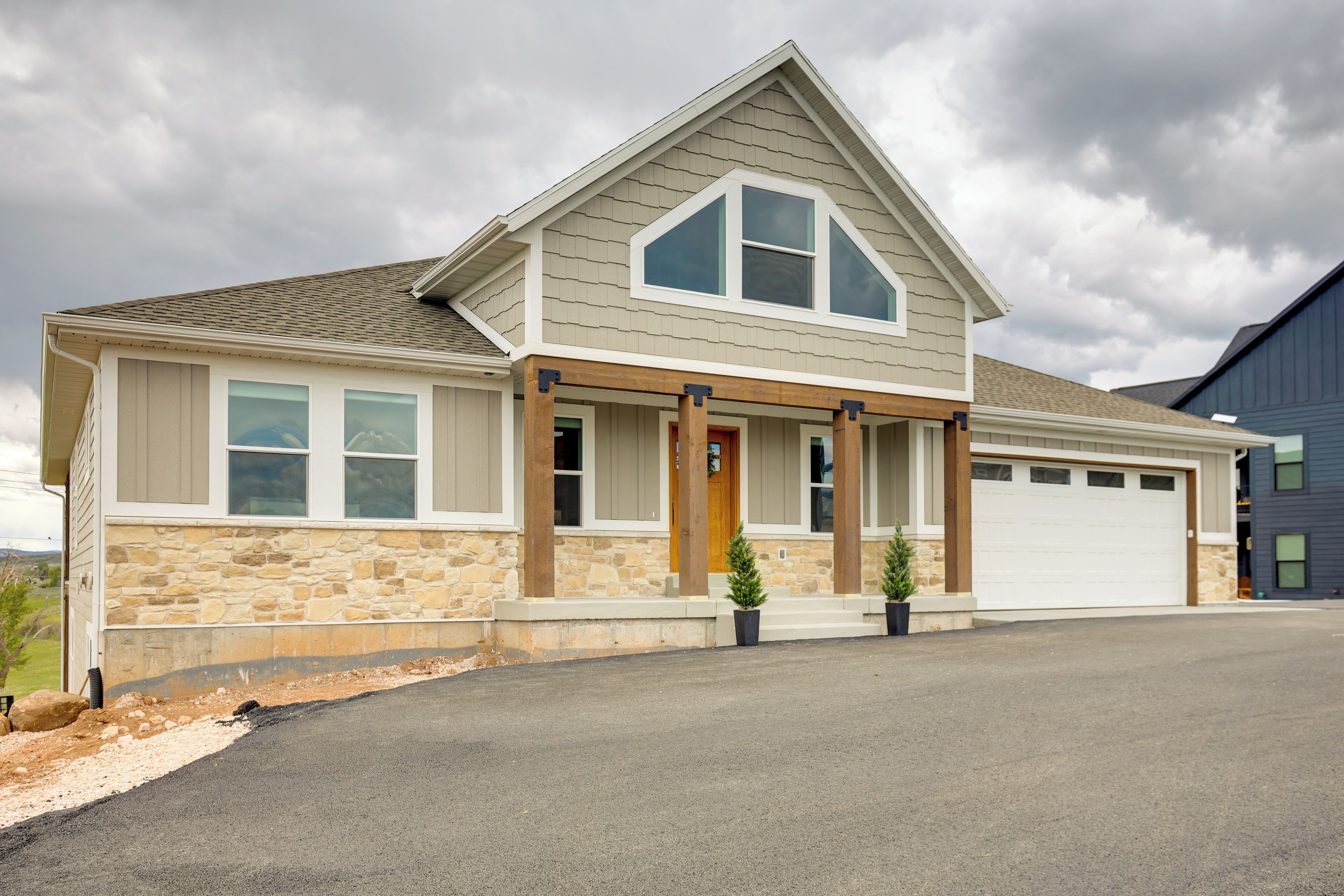 A two-story house with a stone facade, a front porch with columns, and a garage.