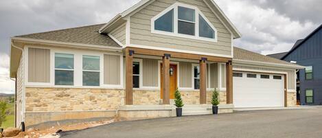 A two-story house with a stone facade, a front porch with columns, and a garage.