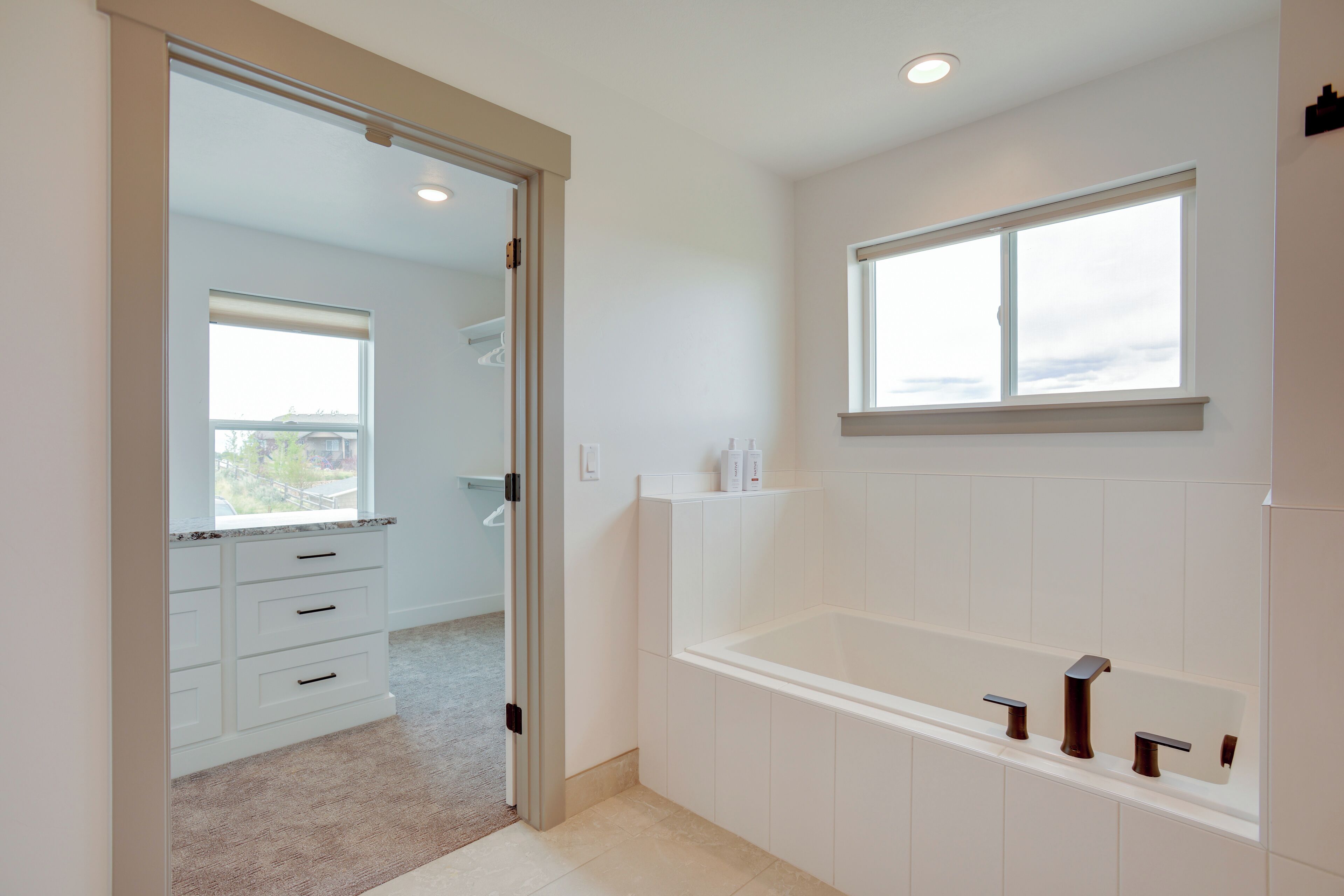 Une salle de bain moderne avec une baignoire, une fenêtre et un dressing.