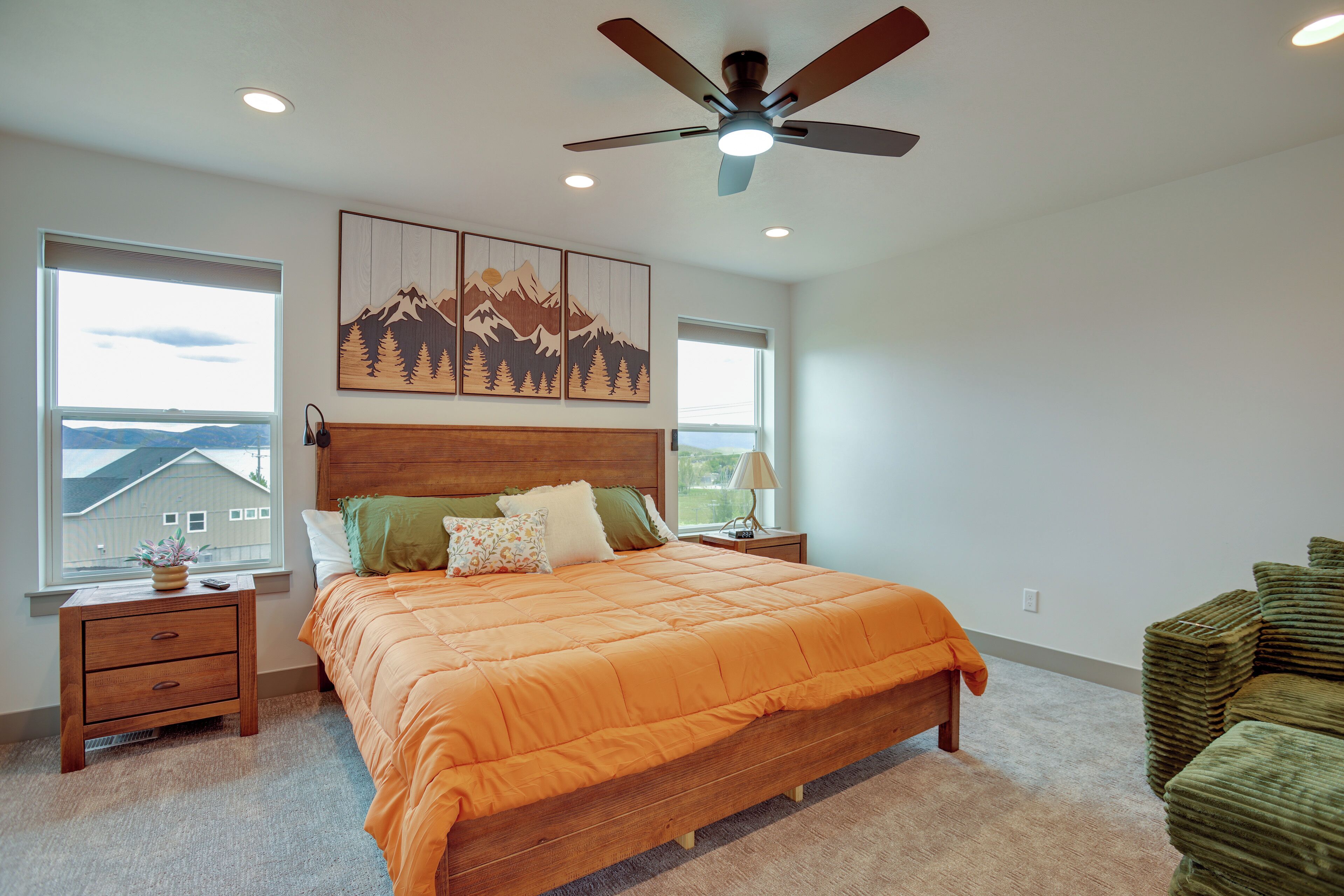 Un dormitorio con cama, mesitas de noche, ventilador de techo y una obra de arte en la pared.