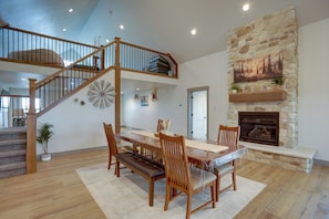 A dining area with a wooden table, chairs, a bench, a stone fireplace, and a staircase. - Ultimate Family Getaway! Luxe 6BR Bear Lake Home (Garden City)