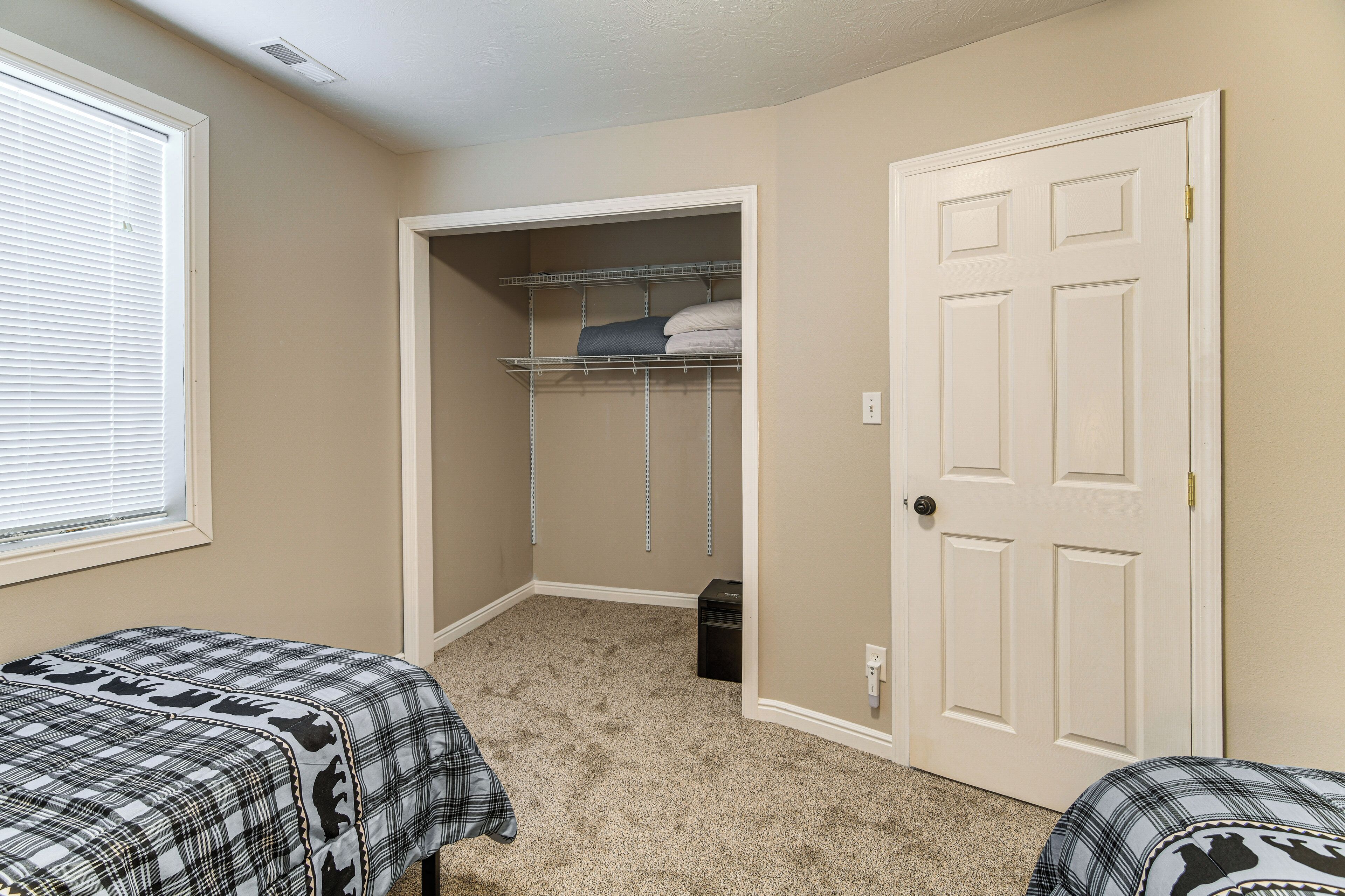 A bedroom with a closet, a bed, and a window.
