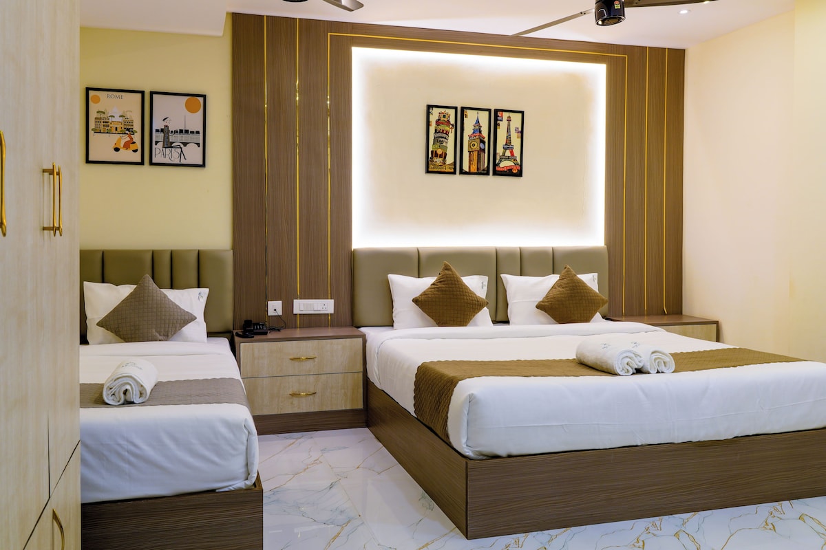 A hotel room with two beds, a wooden headboard, a nightstand, and a wall with framed pictures.
