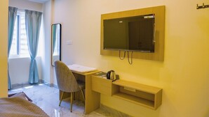 Ein Schlafzimmer mit Bett, Schreibtisch, Stuhl, Spiegel und Fernseher.