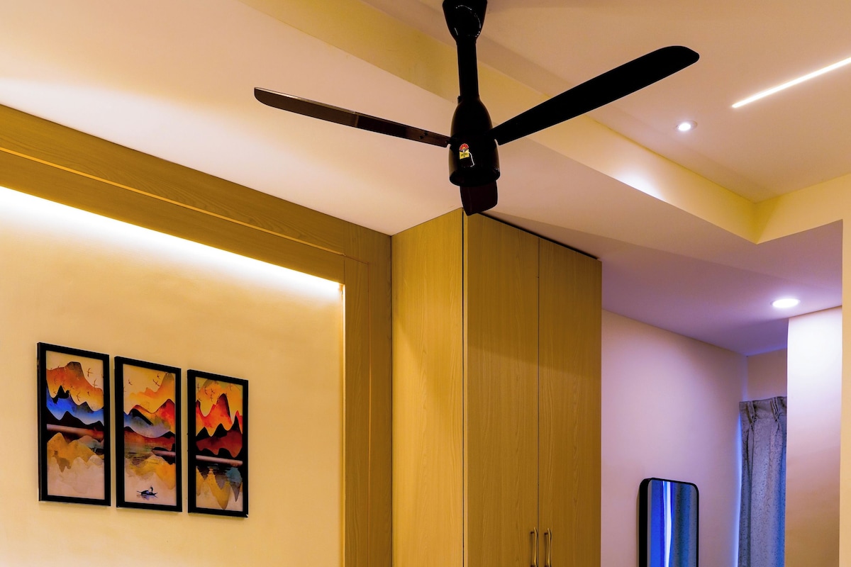 A modern hotel room with a large bed, wooden headboard, and a ceiling fan.