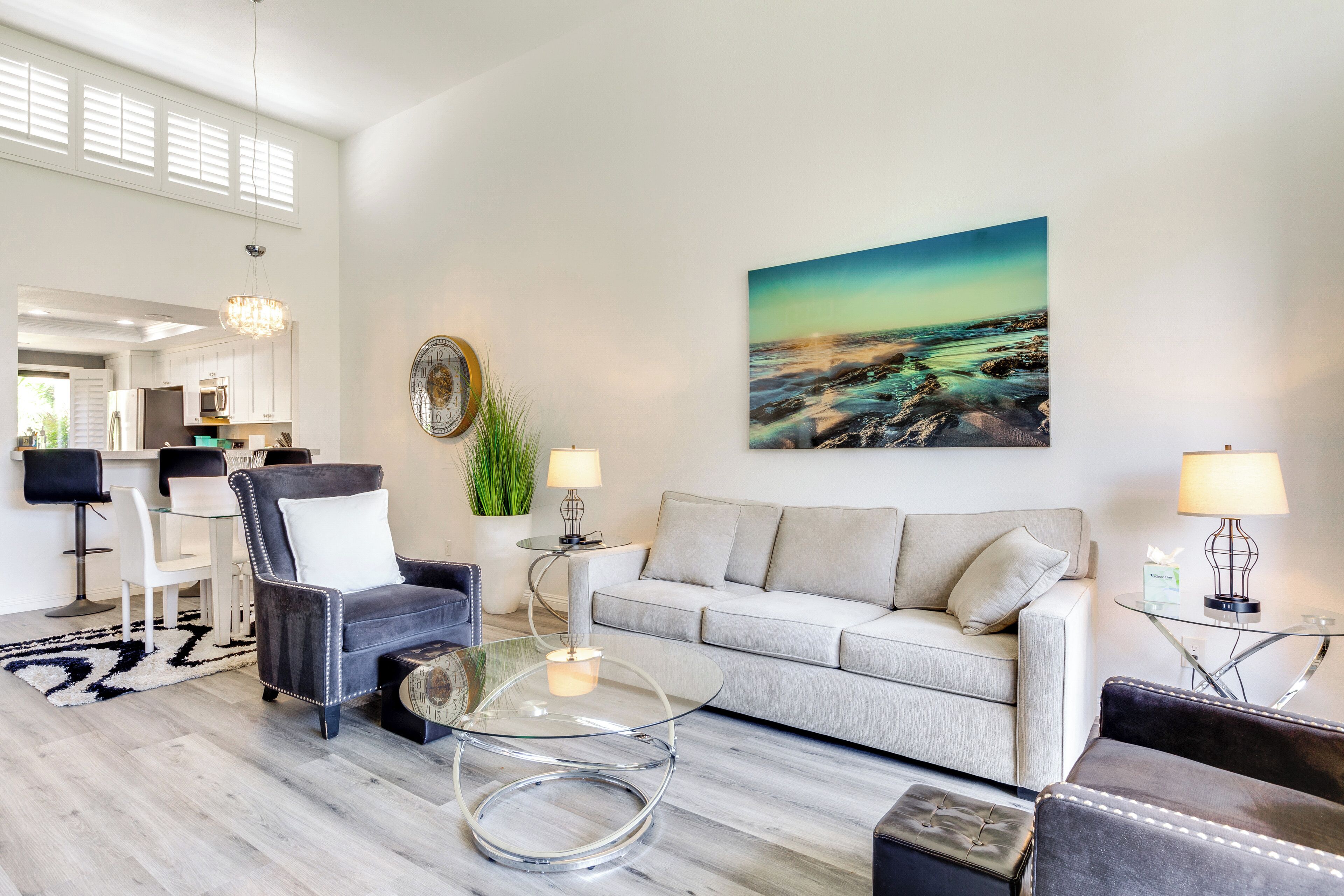 Una sala moderna con sofá, sillón, mesa de centro de vidrio y un comedor con sillas y mesa.