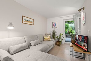 A modern living room with a grey sectional sofa, a flat-screen TV, a floor lamp, and a large window with curtains. - Pet friendly apartment Pergola in Poreč (Porec)