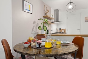 A dining area with a round table, chairs, a plant, and a kitchen in the background. - Pet friendly apartment Pergola in Poreč (Porec)