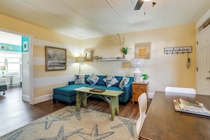 A living room with a teal sofa, a wooden coffee table, a starfish rug, a bookshelf, and a 'welcome' sign. - 2 Blocks to Ocean! North Wildwood Family Getaway (North Wildwood)