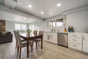 A modern kitchen with a dining table, chairs, and a dishwasher. - Commute to Seattle! Comfortable Apt w/ Sunset View (Federal Way)