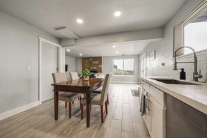A modern kitchen with a wooden dining table, built-in appliances, and a large window. - Commute to Seattle! Comfortable Apt w/ Sunset View (Federal Way)
