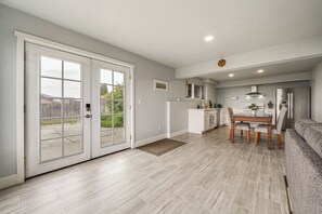 A modern kitchen with a dining area, a sofa, and a sliding glass door leading to a patio. - Commute to Seattle! Comfortable Apt w/ Sunset View (Federal Way)