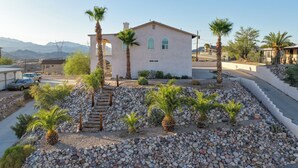 Una casa con patio de piedra, palmeras y una vista despejada de montañas al fondo.