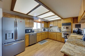 Una cocina moderna con armarios de madera, electrodomésticos de acero inoxidable y un ventanal grande.